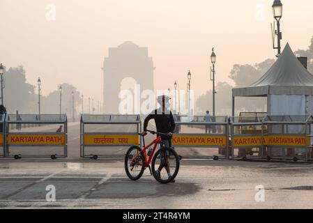 Ein Radfahrer, der eine Maske trägt, die man am India Gate an einem frühen Smoke Morgen gesehen hat. Die Luftverschmutzung in Delhi ist in erster Linie auf Fahrzeuge, Industrien, Baustaub, Abfallverbrennung und Verbrennung von Erntegutrückständen zurückzuführen. Im Winter verschärfen Temperaturumkehrungen das Problem, indem Schadstoffe in Bodennähe eingeschlossen werden. Stockfoto