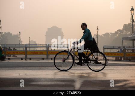 Ein Radfahrer, der zur Arbeit geht, gesehen am India Gate an einem frühen Smoke Morgen. Die Luftverschmutzung in Delhi ist in erster Linie auf Fahrzeuge, Industrien, Baustaub, Abfallverbrennung und Verbrennung von Erntegutrückständen zurückzuführen. Im Winter verschärfen Temperaturumkehrungen das Problem, indem Schadstoffe in Bodennähe eingeschlossen werden. Stockfoto