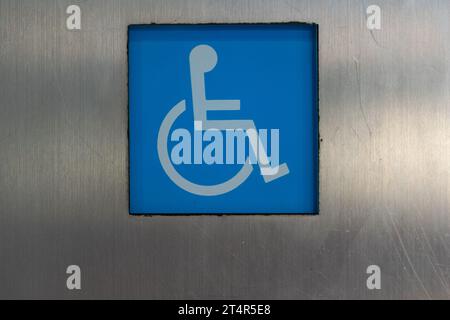 Blaues Schild für Zugänglichkeit an der silbernen Wand des modernen Gebäudes an der Stadtstraße Stockfoto