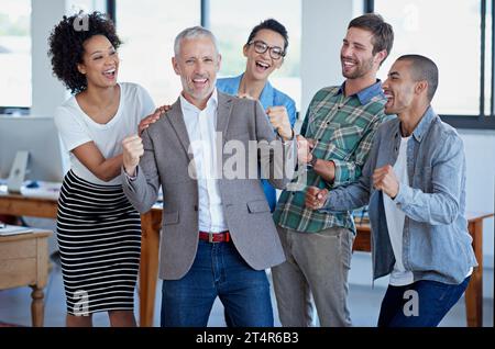 Eine weitere Erfolgsgeschichte. Eine Gruppe glücklicher Kollegen, die in einem Büro stehen. Stockfoto