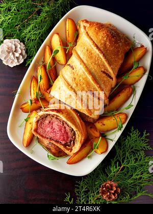 Köstliches Rindfleisch wellington serviert mit gebackenen Kartoffeln und Mikrogrün. Klassisches Steakgericht, großartiges Herzstück für besondere Anlässe. Stockfoto