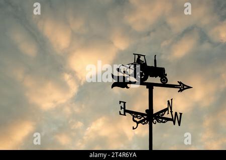 Windschaufeln sind in der Regel dekorativ mit Buchstaben, die die Punkte des Kompasses angeben. Das hier hat ein Traktormotiv und ist in Megs Croft Long Preston. Stockfoto