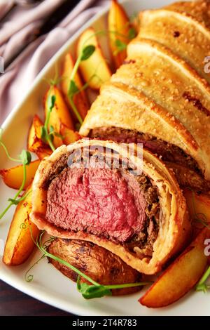 Köstliches Rindfleisch wellington serviert mit gebackenen Kartoffeln und Mikrogrün. Klassisches Steakgericht, großartiges Herzstück für besondere Anlässe. Stockfoto