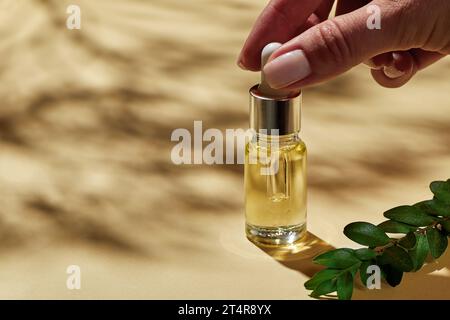 Flaschen zum Öffnen der Hand für Frauen mit Öl für die Gesichtsmassage. Spa-Kosmetik, Minimalismus-Schönheit und Salontherapie-Konzept. Stockfoto