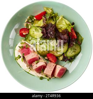 Seltene gebratene Thunfischscheiben mit frischem Gemüsesalat in einer Schüssel. Isoliert auf weißem Hintergrund Stockfoto