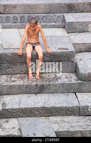 Kathmandu, Nepal: Das nepalesische hindu-Kind ruht auf der Treppe, nachdem es in den heiligen Bagmati-Fluss eingetaucht ist, bei der Einäscherungszeremonie im Pashupatinath-Tempel, Hindu Stockfoto