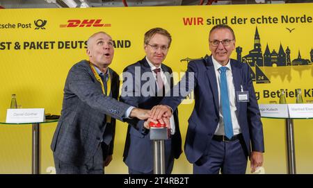 01. November 2023, Schleswig-Holstein, Neumünster: Ingo Kusch (l-r), Niederlassungsleiter Deutsche Post DHL Kiel, Daniel Günther (CDU), Ministerpräsident Schleswig-Hostein, und Manfred Eisenträger, Business Unit Manager Nord der Deutschen Post DHL, starten im Neumünster Paketzentrum eine neue Sortieranlage. Hier werden fast alle Pakete für Empfänger in Schleswig-Holstein und fast alle Sendungen aus Schleswig-Holstein sortiert. Foto: Markus Scholz/dpa Stockfoto