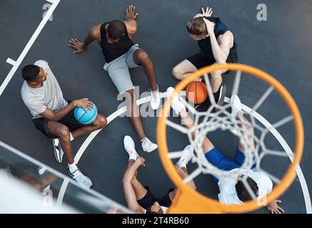 Der Sport spielt eine wichtige Rolle bei der Zusammenführung der Gemeinschaften. Hochwinkelaufnahme einer Gruppe sportlicher junger Männer, die auf einem Basketballfeld rumhängen. Stockfoto