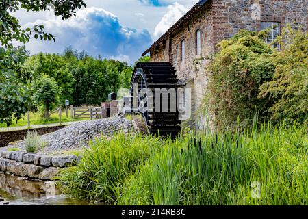 Alte EPER oder Wingbergermolen Wassermühle am Fluss Geul, wildes Gras und Bäume auf dem Grundstück vor wolkenbedecktem blauem Himmel im Hintergrund, sonniger Sommertag in T Stockfoto