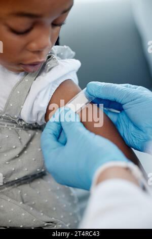 Sie bekommen ihre routinemäßige Kinderimpfung. Nahaufnahme eines nicht erkennbaren Arztes, der nach einer Injektion ein Pflaster auf einen Arm eines kleinen Mädchens aufträgt. Stockfoto