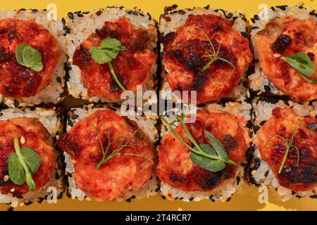 Blick von oben auf japan heiß gebackene Suchi-Brötchen mit Lachs, Gurke und Frischkäse auf gelbem Hintergrund. Stockfoto
