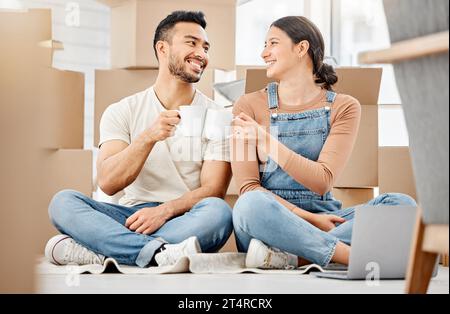 Feuern Sie uns an, damit das alles wahr wird. Ein junges Paar, das auf dem Boden sitzt und Kaffee trinkt, während er umzieht. Stockfoto