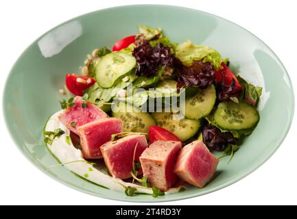 Seltene gebratene Thunfischscheiben mit frischem Gemüsesalat in der Schüssel, isoliert auf weißem Hintergrund. Stockfoto