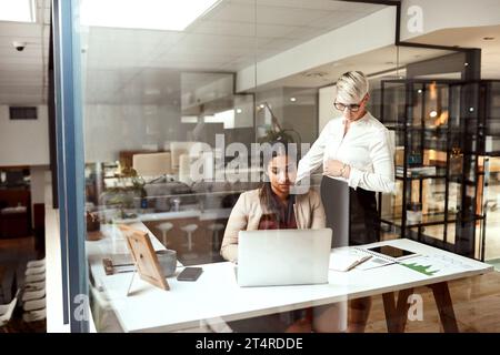 Stellen Sie sicher, dass alles korrekt ausgeführt wird. Zwei Geschäftsfrauen arbeiten zusammen an einem Laptop in einem Büro. Stockfoto