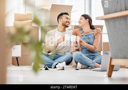 Ich bin so glücklich, dass ich mit dir einen Neuanfang machen kann. Ein junges Paar, das auf dem Boden sitzt und Kaffee trinkt, während er umzieht. Stockfoto