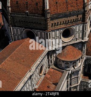 Kathedrale von Florenz, Toskana, Italien: Rote Ziegeldächer und Fußweg, zusammen mit Okuli und weißem Marmor. Oben auf dem Bild befindet sich die raue Ziegelbasis auf sieben Seiten der achteckigen Kuppel der Kathedrale, unter den Terrakottafliesen und Rippen aus weißem Marmor. 1507 begann Baccio d’Agnolo (1462–1543) mit dem Anbau eines Balkons an der Basis der Kuppel; 1515, als jedoch nur an einer der acht Seiten der Kuppel ein Balkon hinzugefügt wurde, verhöhnte Michelangelo das Aussehen des Balkons und die Arbeit wurde gestoppt. Stockfoto