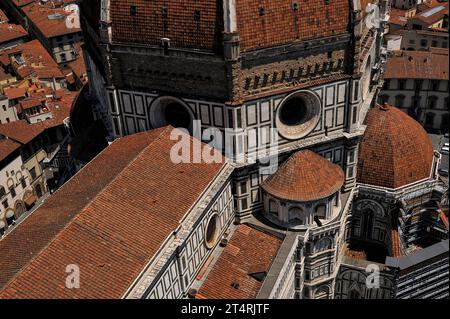 Duomo di Firenze, Toskana, Italien: Rote Ziegeldächer und Fußwege, zusammen mit Okuli und weißem Marmor. Oben auf dem Bild befindet sich die raue Ziegelbasis auf sieben Seiten der achteckigen Kuppel der Kathedrale, unter den Terrakottafliesen und Rippen aus weißem Marmor. 1507 begann Baccio d’Agnolo (1462–1543) mit dem Anbau eines Balkons an der Basis der Kuppel; 1515, als jedoch nur an einer der acht Seiten der Kuppel ein Balkon hinzugefügt wurde, verhöhnte Michelangelo das Aussehen des Balkons und die Arbeit wurde gestoppt. Stockfoto