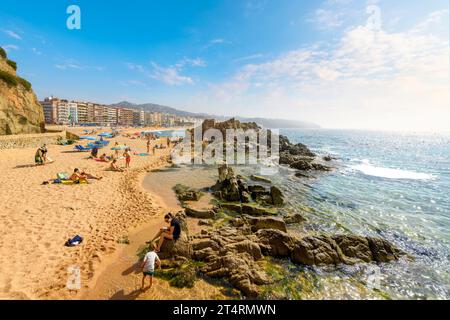 Spanier und Touristen genießen einen Sommertag am breiten Sandstrand Playa Grande im spanischen Ferienort Lloret de Mar an der Costa Brava. Stockfoto