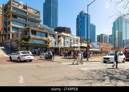 Fußgänger genießen einen sonnigen Tag am Pike Place Eingang zu der beliebten Touristenattraktion entlang des Hafenviertels, Seattle Washington. Stockfoto