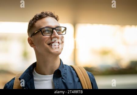 Porträt des glücklichen überraschten jungen kaukasischen Curly man Studenten in Brille mit Rucksack Lifestyle genießen Stockfoto