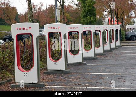 Linie ungenutzter Tesla-Elektrofahrzeug-Hochgeschwindigkeits-EV-Ladegeräte im Rastplatz der Autobahn M4 an der Anschlussstelle 47. Stockfoto