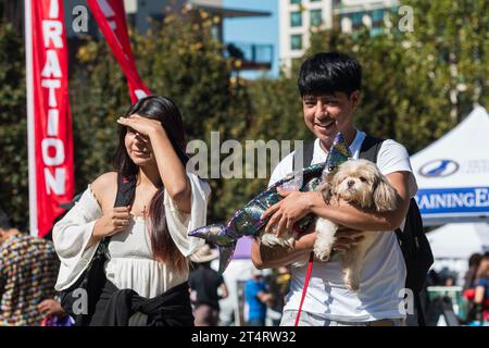 Atlanta, GA / USA - 21. Oktober 2023: Ein Mann trägt einen kleinen Hund, gekleidet wie eine Meerjungfrau, bei einem Halloween-Kostümevent in einem öffentlichen Park in Atlanta, GA. Stockfoto