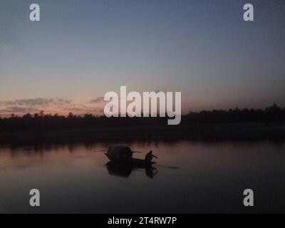 Naogaon, Bangladesch. November 2023. Ein Fischer arbeitet an einem Fischernetz während des Sonnenuntergangs auf dem Atrai River in der Nähe von Dhamoirhat im Bezirk Naogaon. (Kreditbild: © MD Mehedi Hasan/ZUMA Press Wire) NUR REDAKTIONELLE VERWENDUNG! Nicht für kommerzielle ZWECKE! Stockfoto