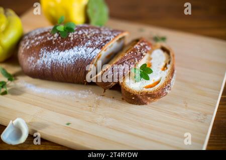 Gekochter süßer Kuchen mit Quitte und Kürbis innen, Hefeteig-Rolle, auf einem Holztisch. Stockfoto