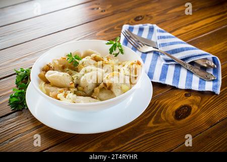 Ukrainischer Vareniky oder Pierogi gefüllt mit Kartoffeln und Pilzen, serviert mit gebratenen Zwiebeln. Holztischhintergrund. Hochwertige Fotos Stockfoto