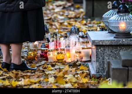 Krakau, Polen. November 2023. Eine Frau und Kerzenlichter werden am 1. November 2023 auf dem Rakowicki-Friedhof in Krakau, Polen, in Glasgläsern gesehen. Allerheiligen in Polen ist ein sehr traditioneller Familienurlaub. Menschenmassen besuchen Friedhöfe im ganzen Land, um Kerzen anzuzünden und Blumen für die Verstorbenen zu bringen. (Foto: Dominika Zarzycka/SIPA USA) Credit: SIPA USA/Alamy Live News Stockfoto