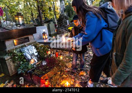 Krakau, Polen. November 2023. Eine Familie zündet am 1. November 2023 auf dem Rakowicki-Friedhof in Krakau, Polen, eine Kerze an. Allerheiligen in Polen ist ein sehr traditioneller Familienurlaub. Menschenmassen besuchen Friedhöfe im ganzen Land, um Kerzen anzuzünden und Blumen für die Verstorbenen zu bringen. (Foto: Dominika Zarzycka/SIPA USA) Credit: SIPA USA/Alamy Live News Stockfoto