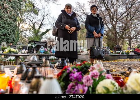 Krakau, Polen. November 2023. Frauen beten am 1. November 2023 an einem mit Blumen und Kerzen geschmückten Grab auf dem Rakowicki-Friedhof in Krakau Polen. Allerheiligen in Polen ist ein sehr traditioneller Familienurlaub. Menschenmassen besuchen Friedhöfe im ganzen Land, um Kerzen anzuzünden und Blumen für die Verstorbenen zu bringen. (Foto: Dominika Zarzycka/SIPA USA) Credit: SIPA USA/Alamy Live News Stockfoto