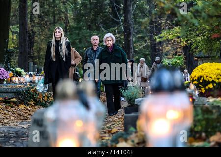 Krakau, Polen. November 2023. Am 1. November 2023 spazieren die Menschen zwischen Gräbern, die mit Blumen und Kerzen geschmückt sind, auf dem Rakowicki-Friedhof in Krakau, Polen. Allerheiligen in Polen ist ein sehr traditioneller Familienurlaub. Menschenmassen besuchen Friedhöfe im ganzen Land, um Kerzen anzuzünden und Blumen für die Verstorbenen zu bringen. (Foto: Dominika Zarzycka/SIPA USA) Credit: SIPA USA/Alamy Live News Stockfoto