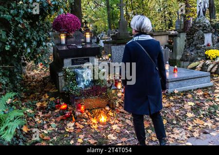 Krakau, Polen. November 2023. Eine Frau steht am 1. November 2023 auf dem Rakowicki-Friedhof in Krakau Polen an einem Grab. Allerheiligen in Polen ist ein sehr traditioneller Familienurlaub. Menschenmassen besuchen Friedhöfe im ganzen Land, um Kerzen anzuzünden und Blumen für die Verstorbenen zu bringen. (Foto: Dominika Zarzycka/SIPA USA) Credit: SIPA USA/Alamy Live News Stockfoto