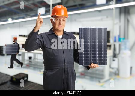 Arbeiter in einer Fabrik, die einen Solarpanel halten und zeigen Stockfoto