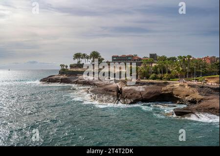 Spektakuläre Küste von Costa Adeja, Teneriffa. Der atlantik stürzt gegen die felsige Landzunge, wo exotische Palmen zu sehen sind. Stockfoto