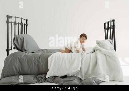 Porträt eines Kindes - ein Mädchen, das auf dem Bett kriecht und spielt. Kinderkonzept. Stockfoto