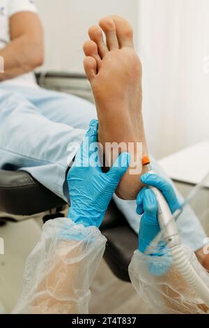 Orthopädischer Arzt in blauen Handschuhen bei der Behandlung der Beine, Nahaufnahme, vertikaler Schuss Stockfoto