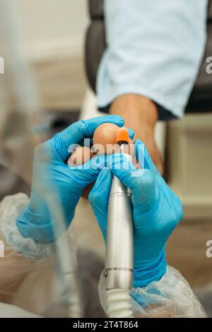Orthopädischer Arzt in blauen Handschuhen bei der Behandlung der Beine, Nahaufnahme, vertikaler Schuss Stockfoto