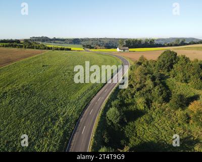 Luftaufnahme einer gekrümmten Straße in der Landschaft an einem sonnigen Morgen Stockfoto