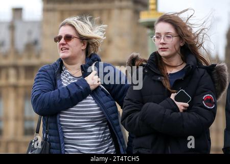 London, Großbritannien. November 2023. Frauen werden bei windigem Wetter auf der Westminster Bridge im Zentrum Londons gesehen. Das Met Office hat eine gelbe Wind- und Regenwarnung für London für Donnerstag ausgegeben, da der Sturm Ciaran wahrscheinlich Böen von bis zu 50 km/h und zwischen 20 und 30 mm Regen in die Hauptstadt bringen wird. (Credit Image: © Steve Taylor/SOPA Images via ZUMA Press Wire) NUR REDAKTIONELLE VERWENDUNG! Nicht für kommerzielle ZWECKE! Stockfoto