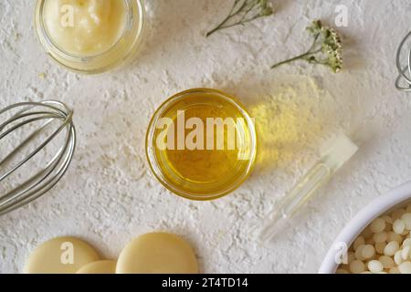 Ätherisches Öl mit Sheabutter, Bienenwachs-Pellets und Kakaobutter auf weißem Hintergrund, Draufsicht Stockfoto