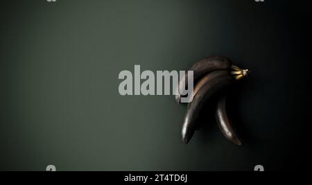 Bananen mit geschwärzter Schale auf dunklem Hintergrund. Schwarzweiß. Minimale künstlerische Komposition. Exklusives Poster in modernem Design. Kopierbereich Stockfoto