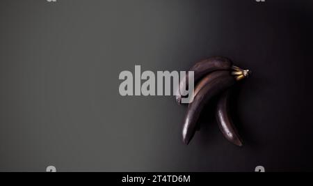 Bananen mit geschwärzter Schale auf dunklem Hintergrund. Schwarzweiß. Minimale künstlerische Komposition. Exklusives Poster in modernem Design. Kopierbereich Stockfoto