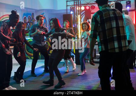 Die Leute feiern im Nachtclub, während sie Spaß haben und gemeinsam auf der Tanzfläche mit Scheinwerfern tanzen. Junge Männer und Frauen besuchen die Diskothek und das Musikkonzert im Club Stockfoto