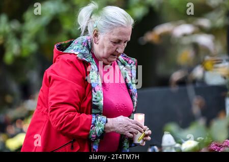 Eine Frau zündet eine Kerze auf dem Rakowicki-Friedhof an. Allerheiligen in Polen ist ein sehr traditioneller Familienurlaub. Menschenmassen besuchen Friedhöfe im ganzen Land, um Kerzen anzuzünden und Blumen für die Verstorbenen zu bringen. Stockfoto