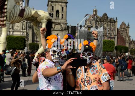 Mexiko-Stadt, Mexiko. November 2023. Touristen mit Schädelmasken machen ein Selfie während des Mega Monumental Opfers des Todestages im Zocalo von Mexiko-Stadt. Am 1. November 2023 in Mexiko-Stadt. (Kreditbild: © Carlos Tischler/OKULARBOGEN via ZUMA Press Wire) NUR REDAKTIONELLE VERWENDUNG! Nicht für kommerzielle ZWECKE! Stockfoto