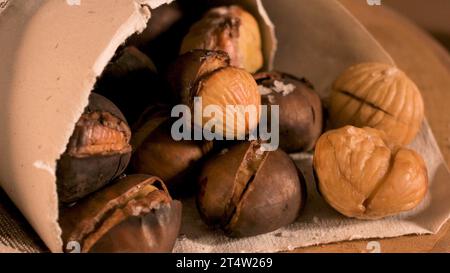 Gebratene Kastanien in einer Papiermembran, auf eine rustikale Küche Arbeitsplatte. Stockfoto