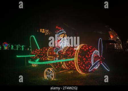 Weihnachtsinstallation strahlender Girlanden. Santa Claus auf einer Helikopterglühanlage. Weihnachtliche Straßendekoration aus Girlanden im Dunkeln Stockfoto