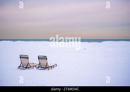 Zwei Liegestühle im Schnee am Ufer des Lake Michigan im Winter Stockfoto